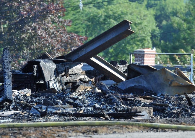 A steel frame sticks out of the remains of a multimillion-dollar home on Mann Street in Hingham that was destroyed by an intense fire that also damaged a neighboring home Monday, July 11, 2022.