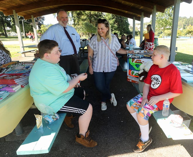The banter between brothers Emmett Eades, 12, left, and Damon Perry, 10, right, brings smiles to Kitsap Superior Court Commissioner Matthew Clucas and parent representation attorney Leyna Harris as they chat with the siblings who were taking part in Family Reunification Day with their mother, Cassandra Eades, at Evergreen-Rotary Park in Bremerton on Monday.