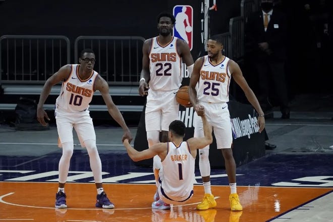 Phoenix Suns forward Jalen Smith (10), center Deandre Ayton (22) and forward Mikal Bridges (25) help guard Devin Booker (1) up during a preseason NBA basketball game against the Los Angeles Lakers, Friday, Dec. 18, 2020,