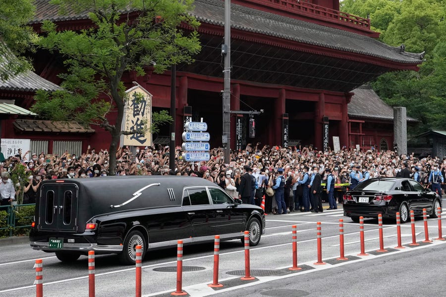 The vehicle, left, carrying the body of former Japanese Prime Minister Shinzo Abe leaves Zojoji temple after his funeral in Tokyo on Tuesday, July 12, 2022. Abe was assassinated Friday while campaigning in Nara, western Japan.