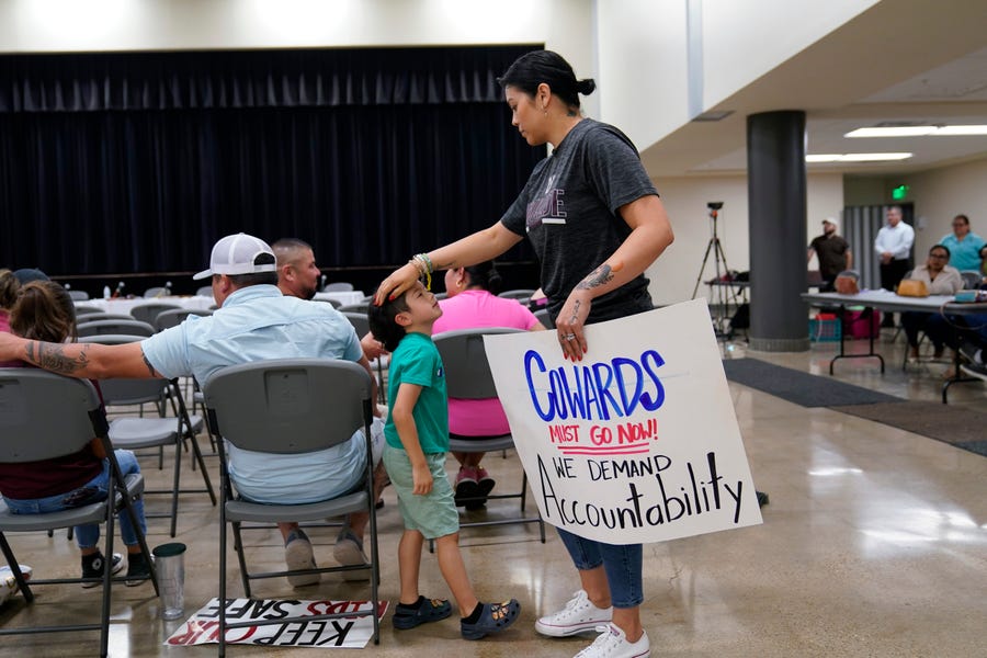 Rachel Martinez, with her son and a protest sign, attends a city council meeting, Tuesday, July 12, 2022, in Uvalde, Texas.