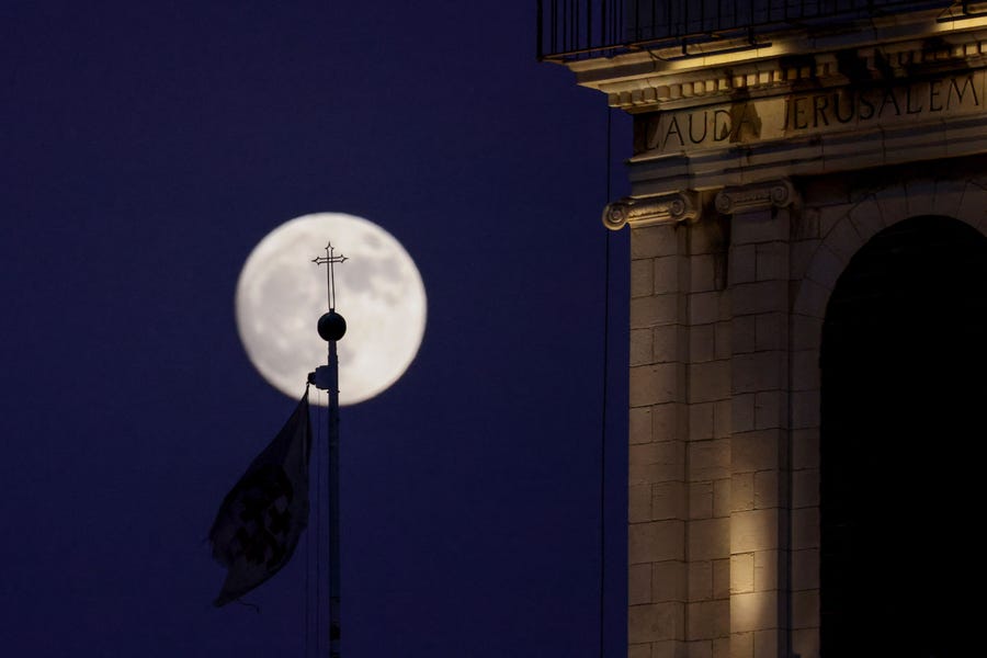 The waxing gibbous moon rises behind a cross  at a church in the old city of Jerusalem On July 12, 2022, a day ahead of the July "buck supermoon".