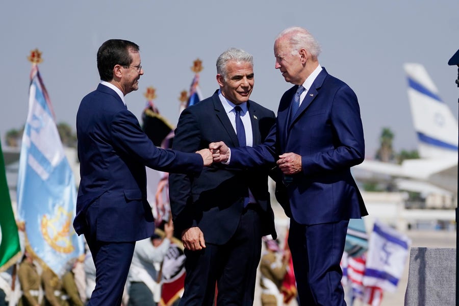 President Joe Biden greets President Isaac Herzog, left, after arriving at Ben Gurion Airport, Wednesday, July 13, 2022, in Tel Aviv, as Israeli Prime Minister Yair Lapid, center, looks on.