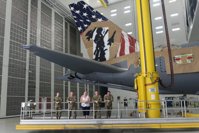 A team of 157th Air Refueling Wing maintenance airmen, along with professional aircraft artist Shayne Meder, pause for a moment in front of their nearly complete custom paint job on the tail of a wing KC-46A, at the 176th Wing's paint booth, Joint Base Elmendorf-Richardson in Alaska on June 29, 2022. From left to right are Airman 1st Class Rebekka Bloser, Tech. Sgt. Jay Cunha, Master Sgt. (retired) Shayne Meder, Staff Sgt. Kevin Canney and Staff Sgt. Cory Lewis.