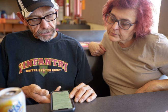 April Hoogerhuies and her husband Daniel Hoogerhuies scroll through emails offering to help them sell their property that have come since the Hermits Peak/Calf Canyon fire started, despite them having no intention to sell, at the Old Memorial Middle School in Las Vegas.