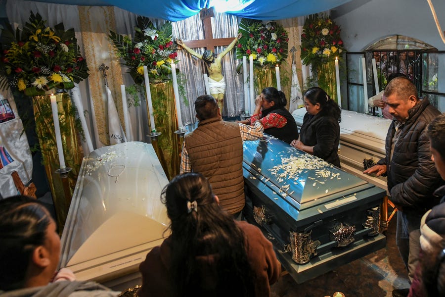 Relatives surround the coffins with the remains of Jair Valencia, Misael Olivares, and Yovani Valencia at their family house in San Marcos Atexquilapan, Veracruz state, Mexico, Wednesday, July 13, 2022. The three were among a group of migrants who died of heat and dehydration in a locked trailer-truck abandoned by smugglers on the outskirts of San Antonio, Texas, on June 27.