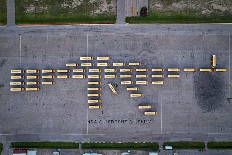 An aerial view of 52 empty school buses, which represent the number of schoolchildren killed by gun violence since 2020, parked to resemble an assault rifle in Houston on July 13, 2022.