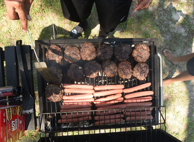 Felix Winston cooks up some burgers and hot dogs during a cookout at Long Leaf Park in Wilmington.