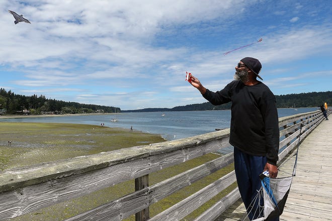 Fudge Pettway, of Bremerton, takes advantage of the windy conditions and flies a kite printed to look like a bird of prey, from the pier at Illahee State Park in Bremerton on Friday, July 15, 2022.