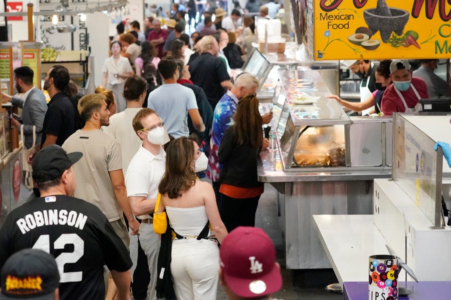 Mask an unmasked patrons walk along a row of food stands inside Grand Central Station Wednesday, July 13, 2022, in Los Angeles. Los Angeles County might be imposing a mandate on July 29 if COVID-19 numbers continue to rise.