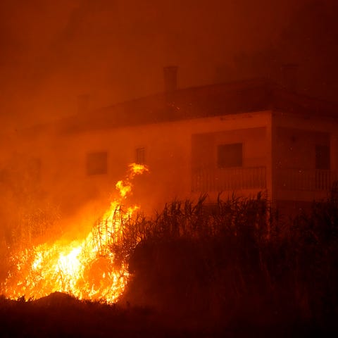 A forest fire reaches an empty house as smoke dark