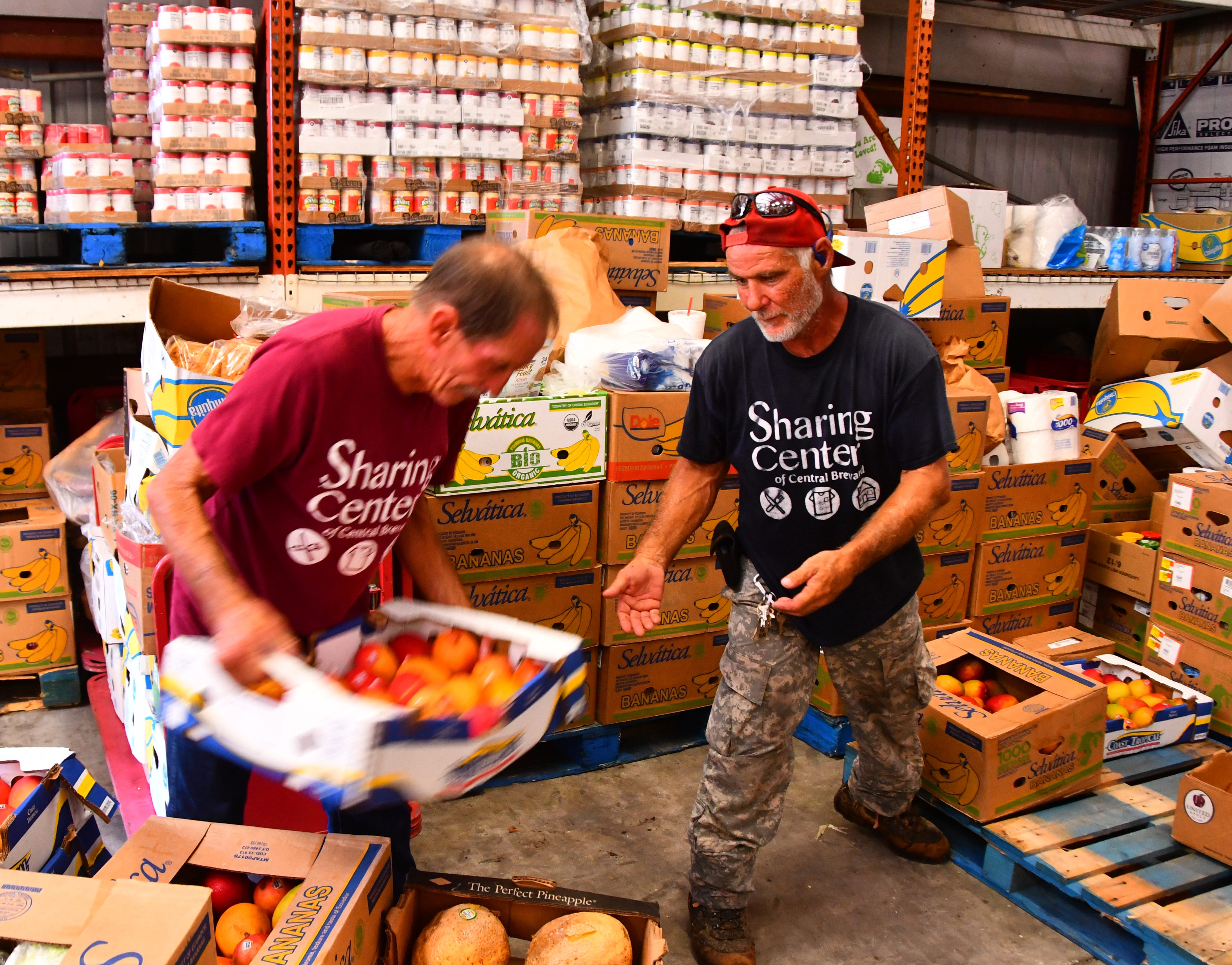 Warehouse workers Mark LeCaptain and Tommy Burns move produce in the warehouse at the Central Brevard Sharing Center.