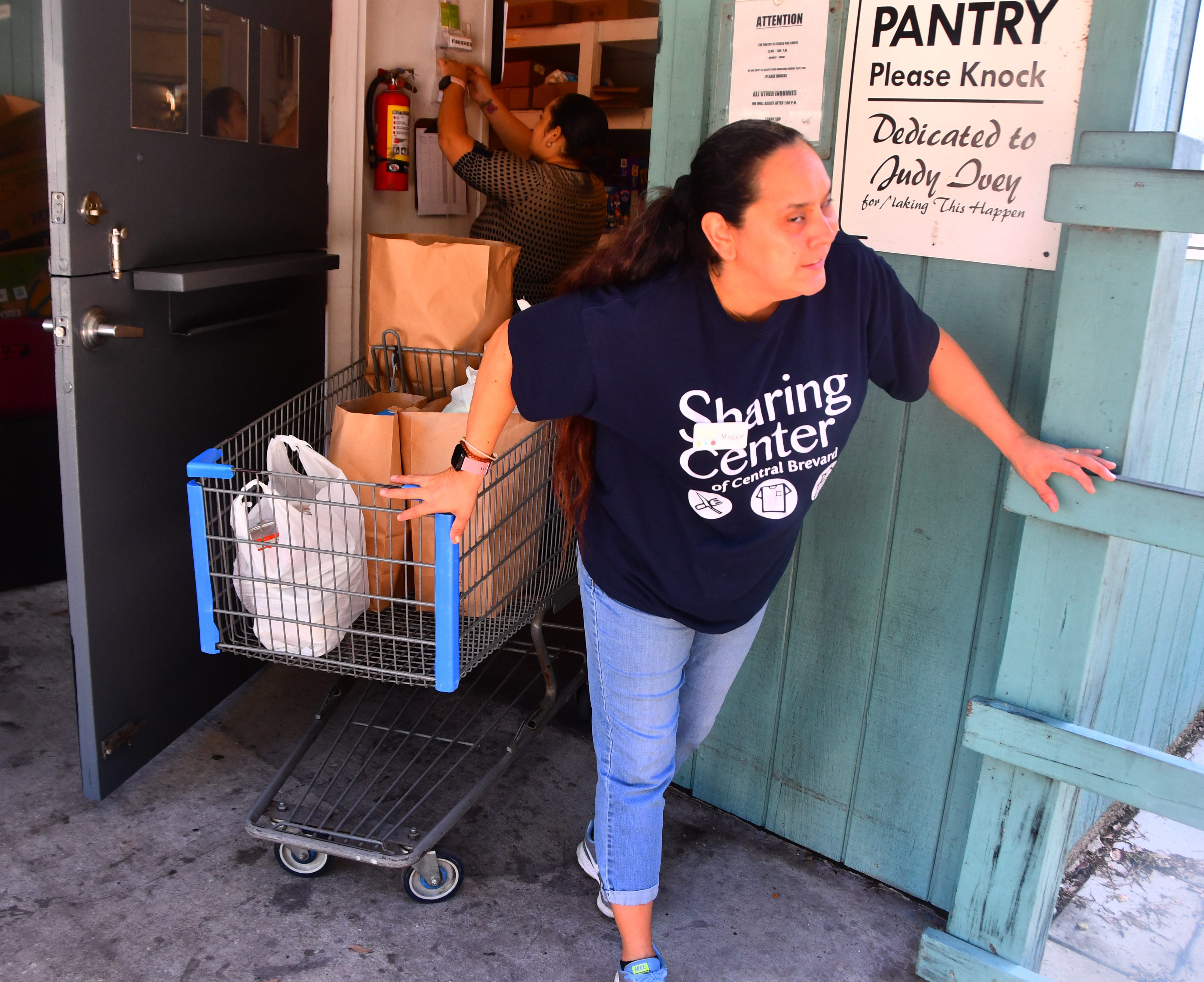 Central Brevard Sharing Center employee Maggie Caro wheels out a cart of groceries for a client.
