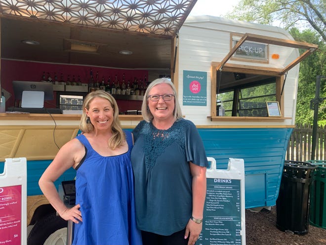Co-owners Stephanie Hayes and Mary Creten pose for a portrait in front of the "Joyride Camper" at the Art of Joy, their new art mercantile and social house, on July 17, 2022. They opened outdoors June 16, and hope to open indoors in September.