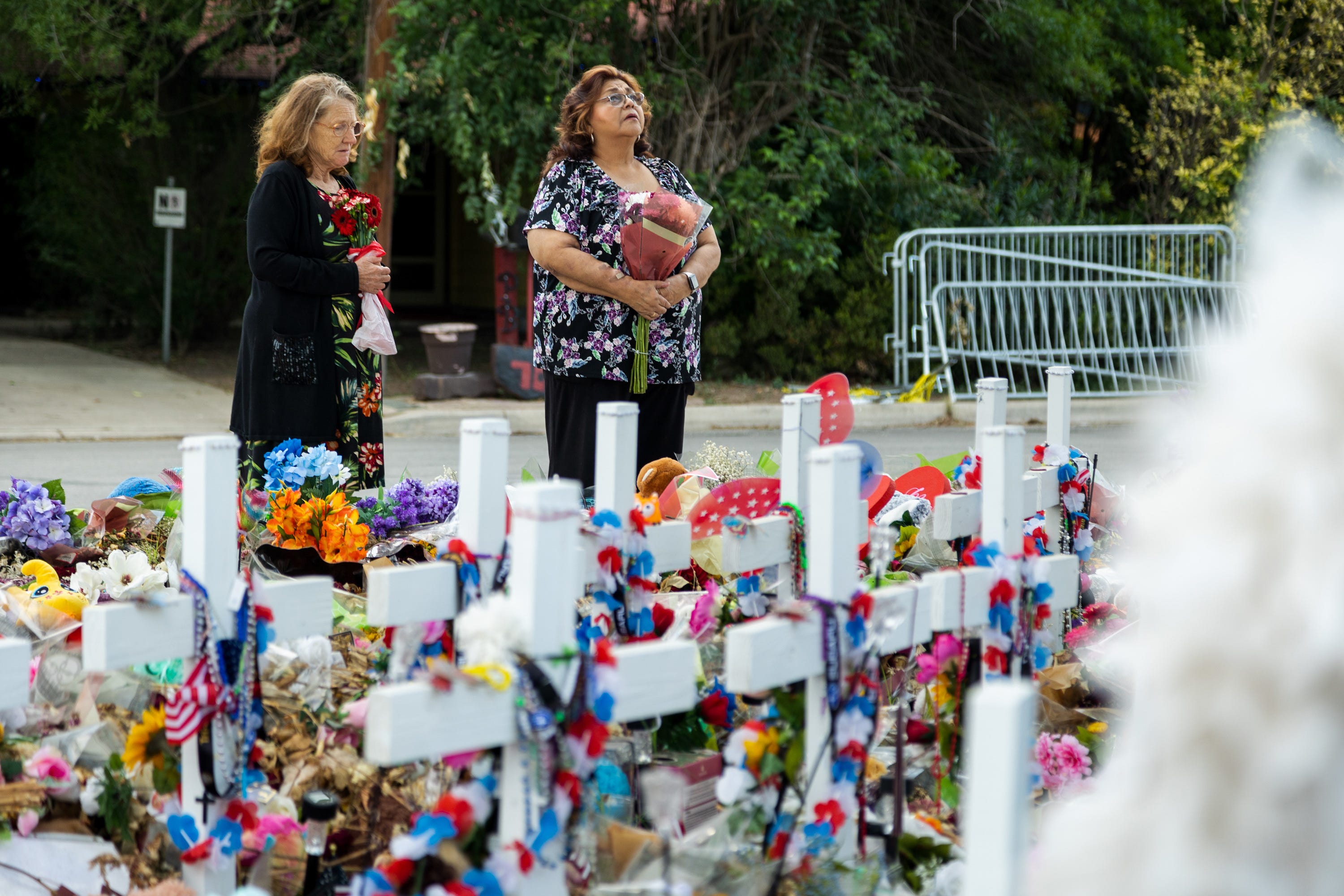 Julie Brown and Irene Marin of San Antonio bring flowers to lay at the memorial for the 21 victims of the school shooting at Robb Elementary in Uvalde, on June 9, 2022.