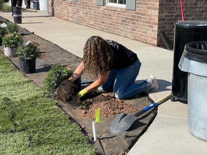 A volunteer plants landscaping around Harry Stokes' future new home. Stokes will be presented with the keys during a ceremony in August.