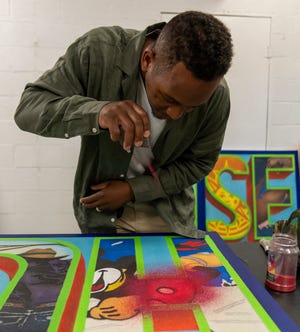 Derrick Carter applies colored sand to art work he’s creating in his studio at Harrison Center, Indianapolis, Thursday, July 14, 2022.