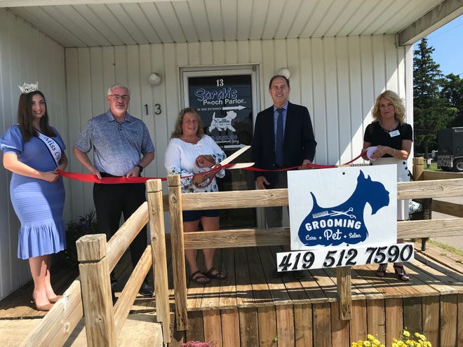 Sarah Blanton, with the scissors, Tuesday celebrated the grand opening of Sarah's Pooch Parlor at 13 E. Whitney Ave., in Shelby with Shelby Mayor Steve Schag at right, and community members.