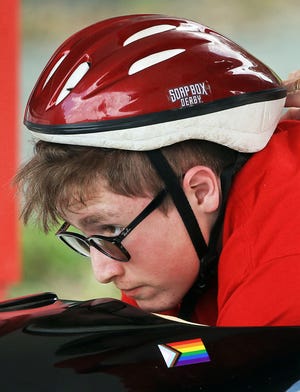 John Barr, 15, of Arlington, Massachusetts, peeks over the front of their derby car as they compete in the the rally super stock division during the third day of the All-American Soap Box Derby at Derby Downs on Wednesday in Akron. John became the first openly nonbinary Soap Box Derby racer after coming out earlier this year.