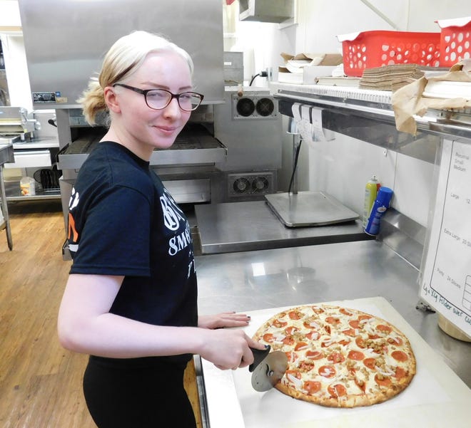 Kaydence Allen slices a pizza in the kitchen at Big C's Smokehouse and Pizza.