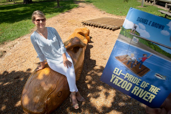 Michele Harris, the event coordinator for the Eli - Pride of the Yazoo River Festival, sits on a wooden sculpture of Eli on Plum Street in Satartia, Miss.. The festival that starts July 30 celebrates the fictitious giant catfish Eli, who is the subject of a children's book written by Daniel Brown.