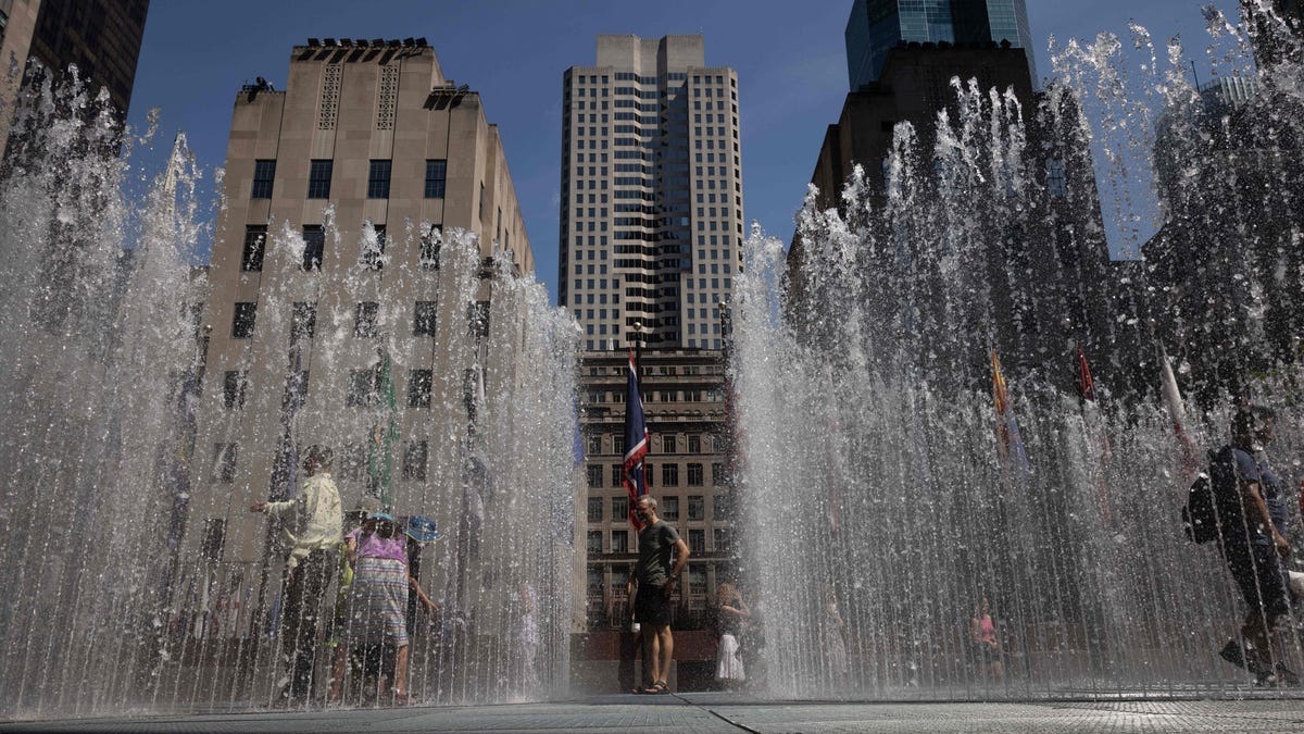 TOPSHOT - People play in the water-based sculpture of artist Jeppe Hein titled "Changing Spaces" at Rockefeller Center Plaza in New York City on July 19, 2022, as a heat wave continues throughout Europe and North America.