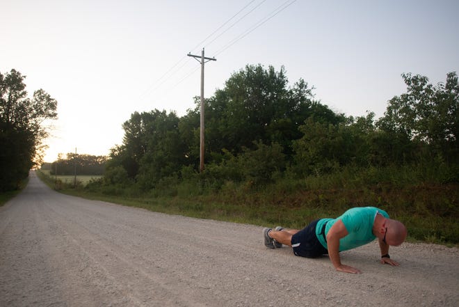 Before sprinting up a hill off S.W. 69th Street and Vorse Road, Damon Parker does pushups Wednesday morning. As part of his training to climb the equivalent of Mount Everest, Parker will run up and down this hill, doing pushups on both ends, as well as stair sets in downtown Topeka buildings.
