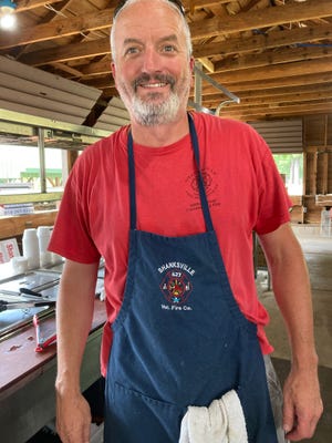 SVFD Captain Brad Shober staffs the grill, frying hundreds of burgers and hot dogs at the Shanksville community picnic. "We firefighters sometimes serve the public in aprons so we can raise funds to buy our bunker gear," he said.