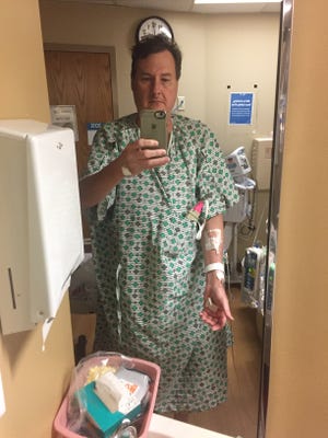 News Journal reporter Mark Caudill takes a selfie in his hospital gown while hooked up to IVs for a blood thinner and a COVID-19 medication.