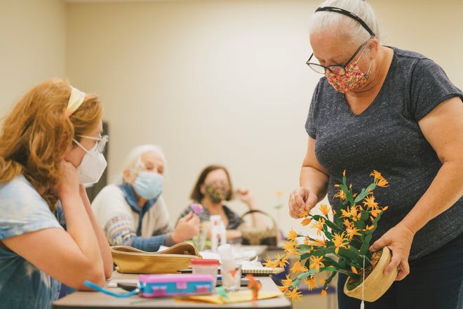 Participants create paper flowers with Linda Majewski at New Castle Public Library.