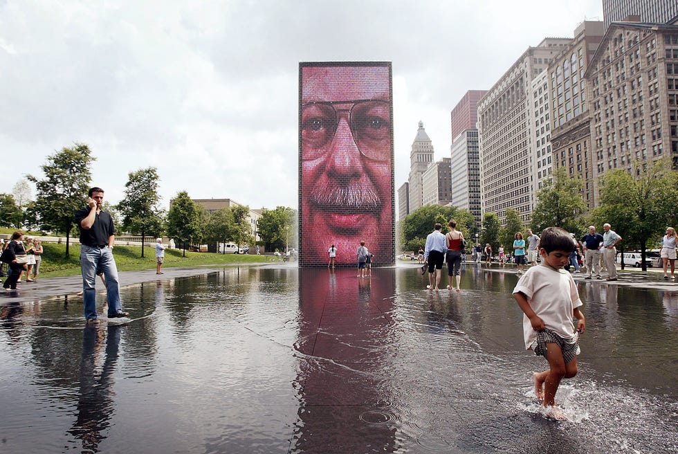 Children and adults explore Crown Fountain sculpted by Jaume Plensa in Millennium Park July 16, 2004, in Chicago, Illinois.