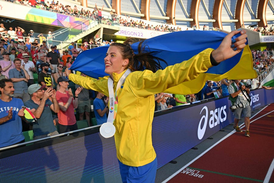 Ukraine's Yaroslava Mahuchikh celebrates with a Ukrainian flag after the women's high jump final during the World Athletics Championships at Hayward Field in Eugene, Oregon on July 19, 2022.