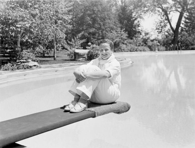 Benson Ford, son of Edsel Ford and grandson of Henry Ford, sitting on the pool dive board in 1934.