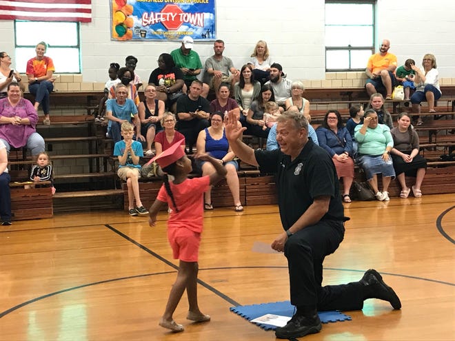 Shaekara Waters high fives interim Mansfield fire Assistant Chief Brian Danals Friday during the Safety Town graduation at the Spanish Immersion School.
