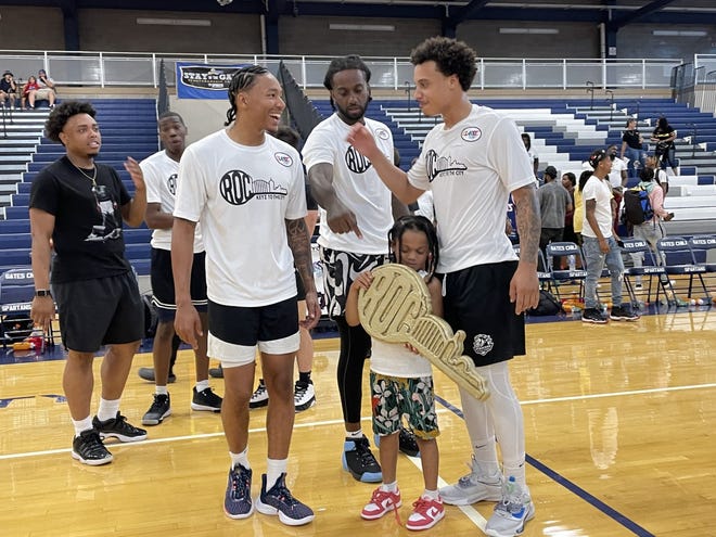 Tap team players and a young fan celebrate their 108-107 victory against Impact team in the professional game Keyz to the City.  The third annual event took place at Gates Chile on Saturday.