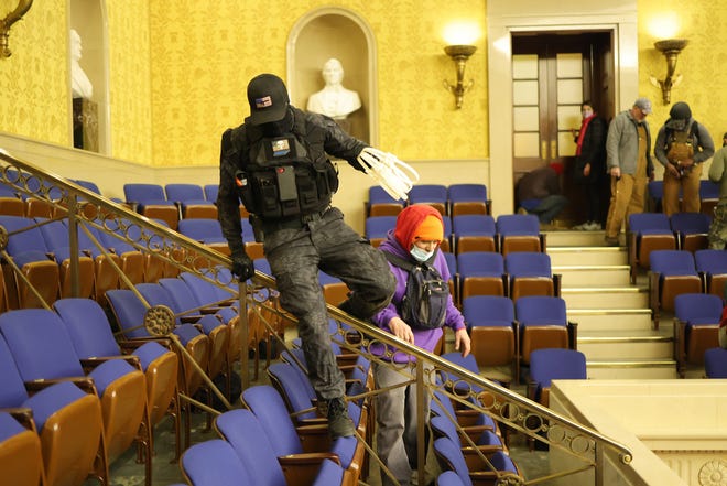 Protesters enter the Senate Chamber on Jan. 6, 2021, in Washington, D.C. Two men photographed carrying zip-ties in the U.S. Capitol Wednesday were charged Sunday in a federal court in the District of Columbia. (Win McNamee/Getty Images/TNS)