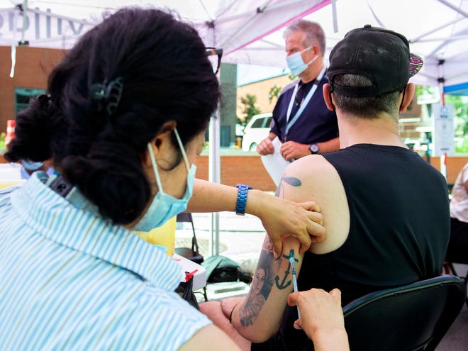 Brian Maci, from New York, receives a monkeypox vaccine at an outdoor walk-in clinic in Montreal, Saturday, July 23, 2022. Tourists are among those lining up to get monkeypox vaccines in Montreal, as the World Health Organization declares the virus a global health emergency.