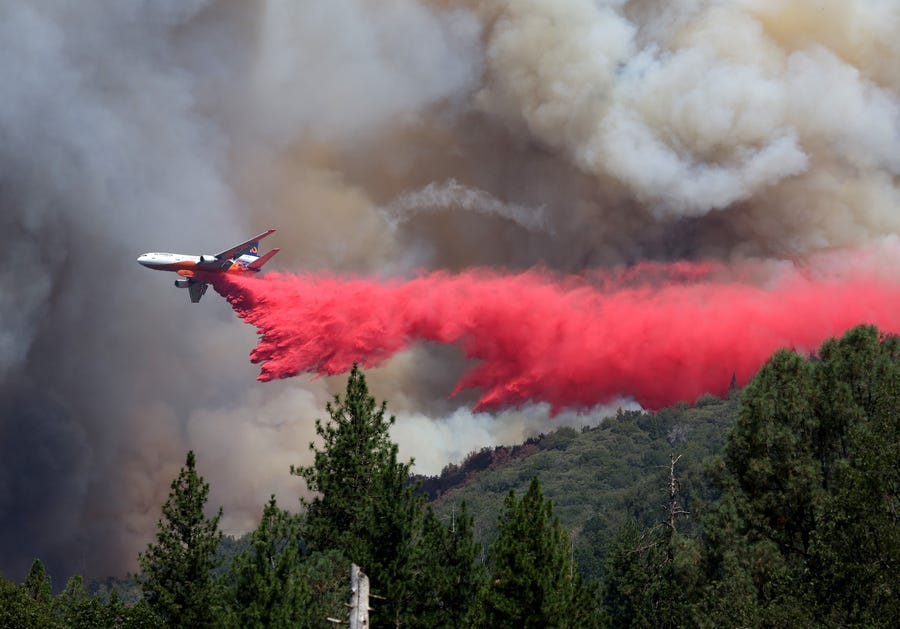 A firefighting aircraft drops retardant ahead of the Oak Fire on July 24, 2022 near Jerseydale, California. The fast moving Oak Fire burning outside of Yosemite National Park has forced evacuations, charred over 14,000 acres and has destroyed several homes since starting on Friday afternoon. The fire is zero percent contained.