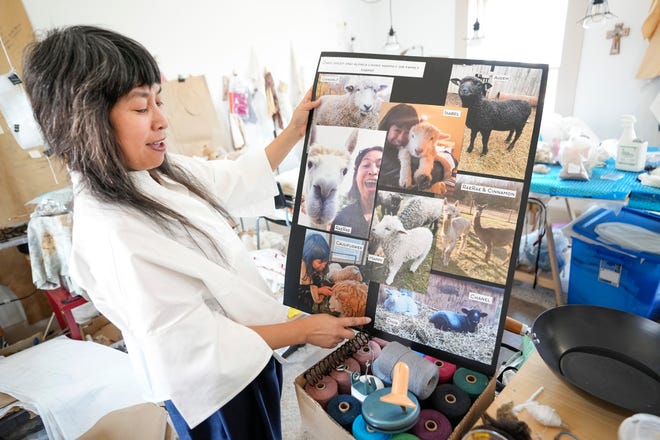 Celeste Malvar-Stewart shows off photos of the local alpacas and sheep from whom she sources her design materials inside her German Village studio on July 22, 2022. Adam Cairns-The Columbus Dispatch