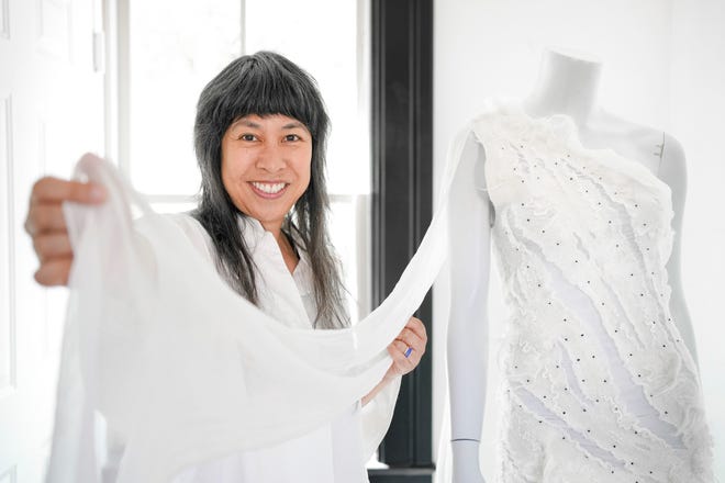 Celeste Malvar-Stewart holds a gown from her "Runway" collection inside Malvar = Stewart Studio in German Village on July 22, 2022. Adam Cairns-The Columbus Dispatch