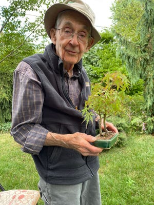 Jack Wikle, who recently turned 90 years old, retired from Hidden Lake Gardens and as a Naturalist Educator and Bonsai Curator. He's holding one of his many beloved bonsai trees.