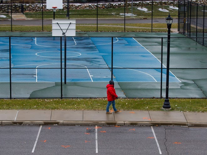 A person walks past markings on the pavement Wednesday, Dec. 16, 2020, near the basketball courts at Central Park in Mishawaka.
