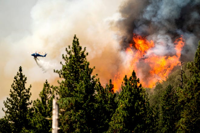 A helicopter drops water while battling a wildfire in Mariposa County in northern California on Sunday.