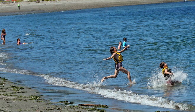 Ten-year-old siblings Athena and Aremis Shepard, of Bremerton, run down the beach and jump into the water at Point No Point in Hansville on Monday.