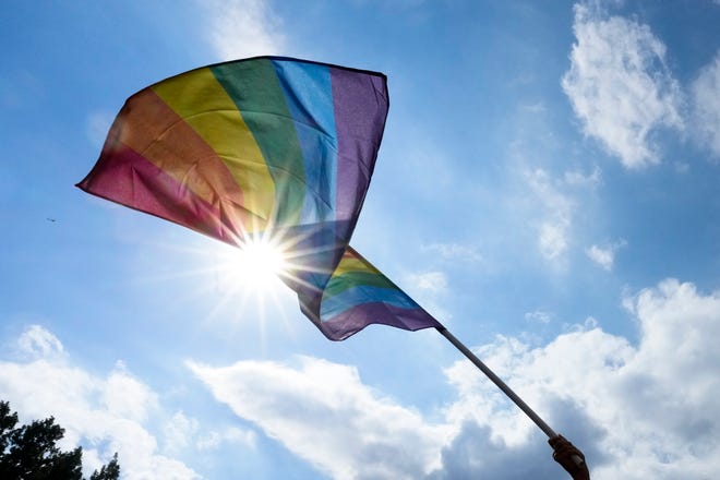 A woman waves a rainbow pride flag.