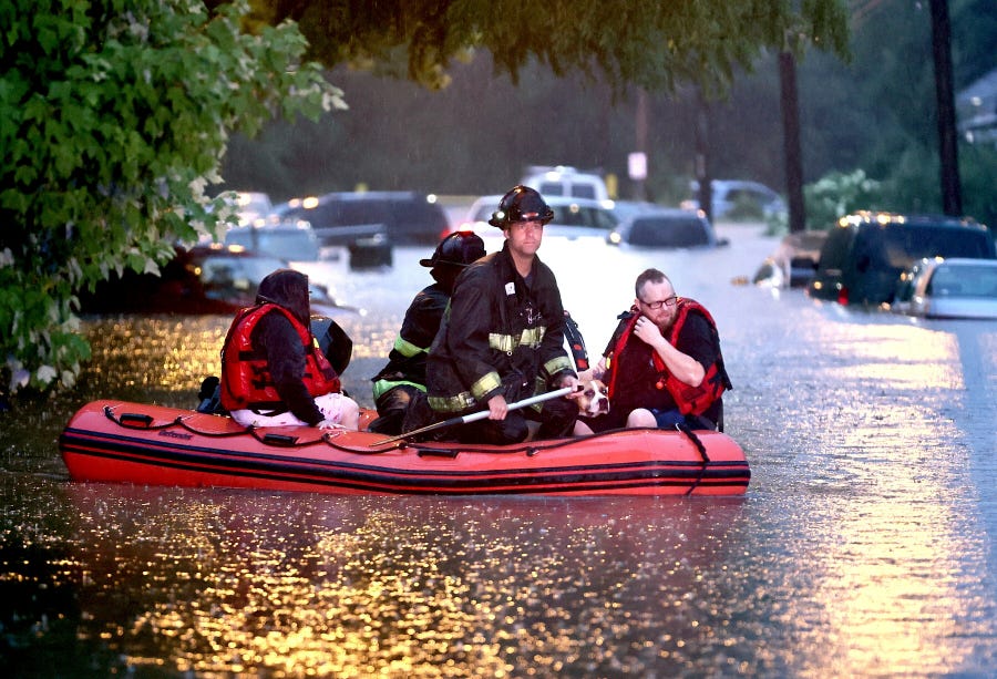 Steven Bertke and his dog Roscoe are taken to dry land by St. Louis firefighters who used a boat to rescue people from their flooded homes on Hermitage Avenue in St. Louis on Tuesday, July 26, 2022. (David Carson/St. Louis Post-Dispatch via AP) ORG XMIT: MOSTP202