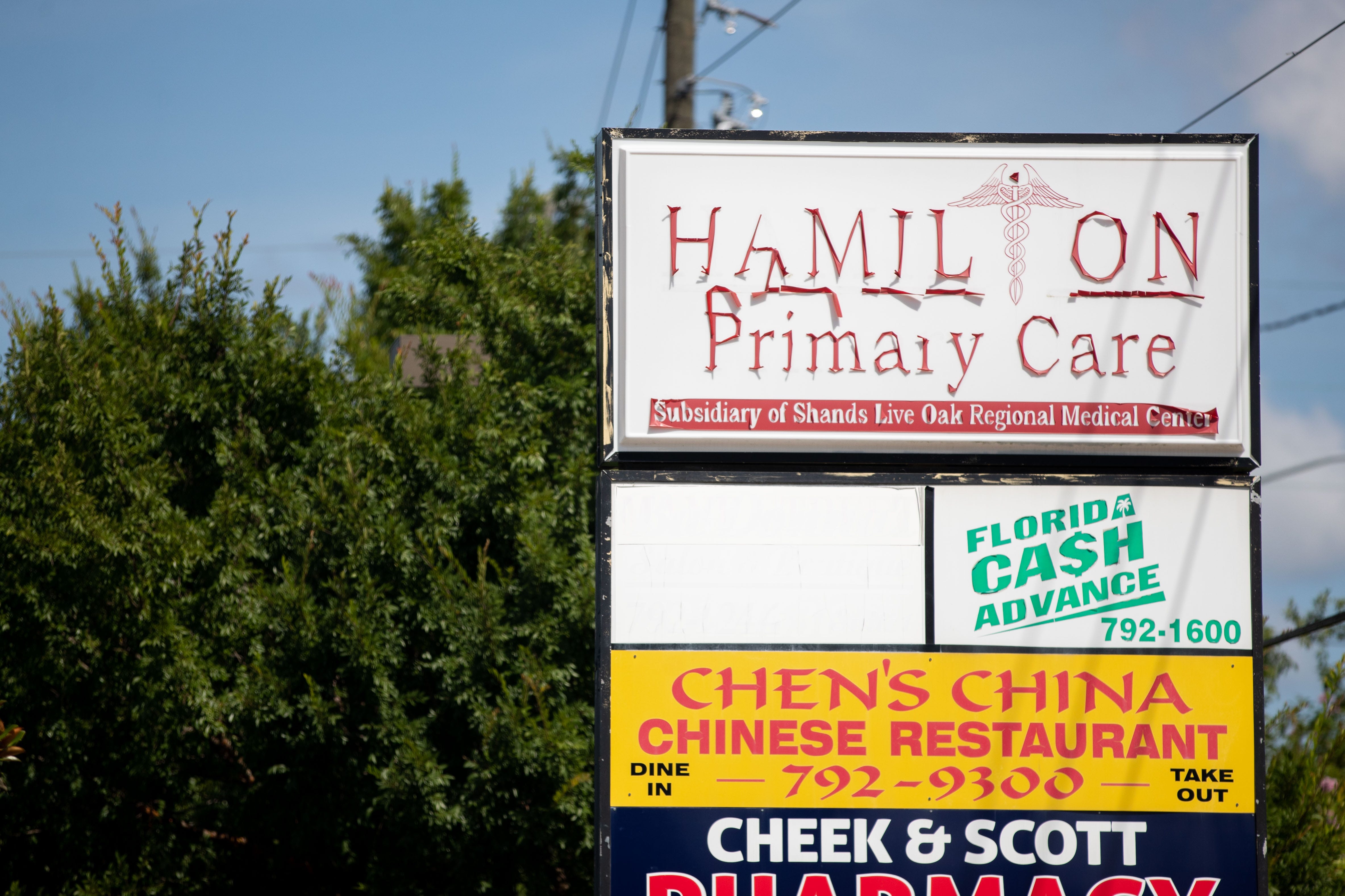 Lettering for a sign for Hamilton Primary Care peels from the surface. The medical practice has vanished from the shopping plaza. 