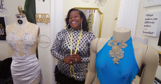 Custom fashion designer Jawanda Evans of Brockton, owner of Werthé by Jem, shows off two of her creations at her studio on Tuesday, July 26, 2022. She specializes in formal and wedding wear, customizing her creations to suit each customer. One of the busiest times of the year for her is prom season, when she gets help from friends and family to keep up with the demand.
