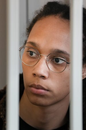 Brittney Griner looking through the bars of a cage in a Russian courtroom.