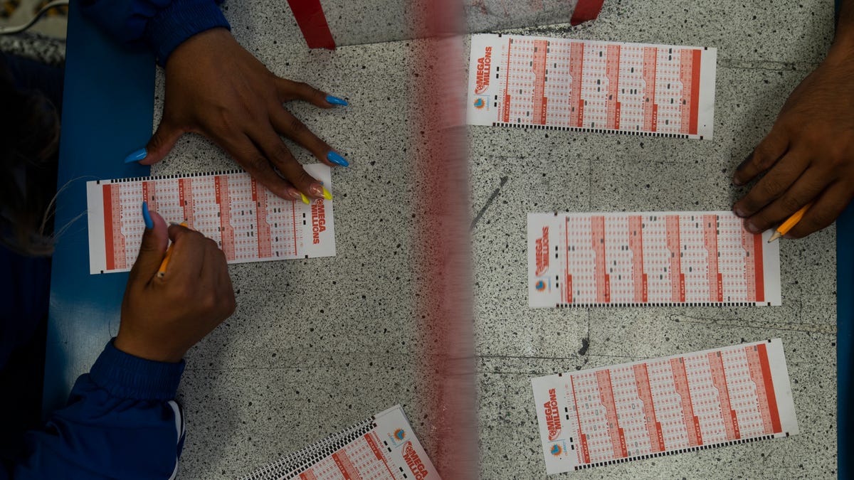 Nancy Linares, left, and Prince Joseph Israel fill out Mega Millions play slips at Blue Bird Liquor in Hawthorne, Calif., Tuesday, July 26, 2022.